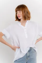 Blusa blanca de lino con escote en V abotonado y mangas cortas arremangadas.