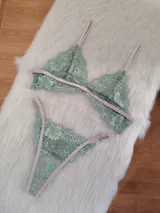 Conjunto de lencería compuesto por un bralette triangular y una bombacha tipo tanga, confeccionados en encaje color verde oliva con detalles y elásticos en tono tostado.