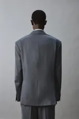 Blazer de corte regular confeccionada en tejido con lana, con cuello de solapas de muesca y manga larga con puños abotonados. Presenta cierre frontal de botonadura y cuatro bolsillos plastrón con solapa en el delantero.