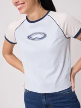 Remera celeste con mangas cortas color crema y cuello redondo con ribete azul marino. Estampado ovalado con logo de la marca en el frente.