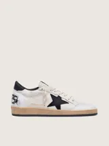 Zapatillas Golden Goose modelo Ball Star, confeccionadas en cuero con efecto desgastado. Diseño en color blanco con estrella lateral en negro, contrafuerte negro y suela de aspecto envejecido.