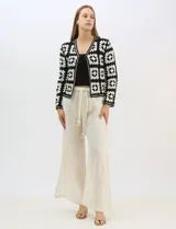 Cardigan abierto de tejido de punto calado con diseño geométrico y floral bicolor. Presenta escote en V, mangas largas y cierre frontal con tiras para anudar. Incluye detalles de vivos a contraste en el contorno del escote, puños y ruedo.
