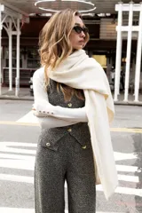 Pantalón de tiro medio, pierna ancha, confeccionado en tejido texturado de color claro con hilo metalizado. Presenta falsos bolsillos delanteros con botones metálicos dorados.