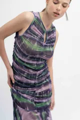 Vestido midi de microtul estampado tipo batik en tonos lila, verde y azul. Presenta fruncido en todo el cuerpo, forro interior y una falda transparente con picos y movimiento.