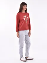 Remera de manga larga color blanco, con cuello redondo y estampa frontal en tono rosado que incluye un diseño de marco con moño y la frase "live simply love sincerely".