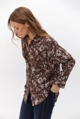 Camisa de corte holgado con estampado floral en tonos marrones y blancos, cuello clásico y cierre frontal con botones.