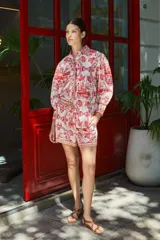 Camisa blanca con estampado de aves, edificios y motivos florales en color rojo.