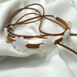 Gargantilla de cuero marrón con flores de acrílico rosado y tiras de cuero para atar.