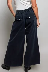 Pantalon de tiro bajo y pierna ancha confeccionado en denim negro con efecto vintage, decorado con ojales metálicos a lo largo de los laterales y los bolsillos.