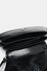 Bolso de hombro tipo baguette con acabado brillante, solapa frontal con cierre de botón imantado y asa ajustable.