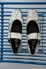 Chatas plateadas de cuero con punta cuadrada, tira sobre el empeine con hebilla metálica y suela plana.