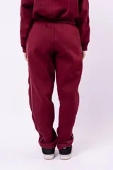 Conjunto deportivo compuesto por una campera con cierre y un pantalón de jogging, ambos de color negro con detalles de líneas blancas laterales. El pantalón presenta un corte holgado y cómodo.