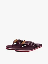 Ojotas de hombre con base de goma EVA color bordó y detalles de líneas rojas y blancas en el borde. Las tiras son de tejido trenzado bordó con franjas blancas y rojas, y tienen un aplique de cuero sintético marrón en el centro.