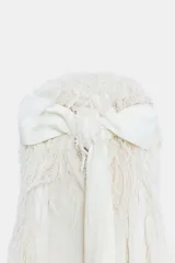 Vestido largo color crudo de cuello halter, sin mangas y con textura de flecos en toda la prenda. Cuenta con espalda descubierta, cierre de botones y lazada a contraste.