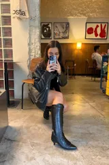 Botas altas de caña alta negras confeccionadas en PU, con diseño acordonado frontal, punta fina, cierre lateral y taco bajo fino.