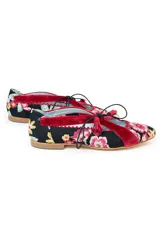 Zapatos tipo blucher de diseño artesanal, confeccionados en algodón con estampado floral multicolor sobre base negra. Presentan detalles en terciopelo color fresa, cierre con cordones rematados en borlas y suela de cuero.