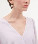 Blusa de poliéster color lila con transparencia, escote en V y mangas largas abullonadas con puños elásticos.