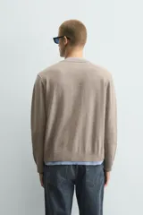 Cárdigan de punto con cuello en pico y manga larga. Presenta un diseño de ajuste relajado con cierre frontal de botones y acabados en rib con efecto doble en color azul a contraste sobre la base color topo.