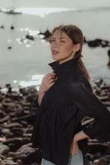 Blusa negra de lino con cuello mao, mangas largas y alforzas verticales en el frente.