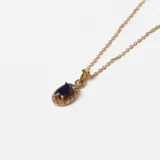 Collar de oro 18k con cadena fina de eslabones y dije ovalado central que presenta un zafiro azul rodeado por pequeños brillantes.