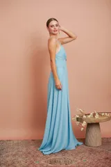 Vestido largo de gasa color celeste, con escote en V profundo y tirantes finos. Presenta una falda larga con gran caída y movimiento.
