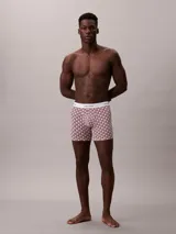 Pack de tres bóxers largos Calvin Klein modelo Icon Cotton Stretch. Incluye un bóxer liso en color rosado claro, uno estampado con patrón geométrico en tonos bordo y blanco, y uno negro liso. Todos cuentan con cintura elástica con el logo de la marca en contraste.