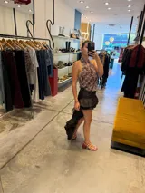 Falda marrón de estilo asimétrico, corta en la parte delantera y larga en la parte trasera, con múltiples volados y diseño de capas.