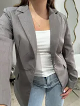 Blazer sastrero de corte clásico en color gris, con solapas de muesca, cierre frontal de un botón y bolsillos laterales con solapa.