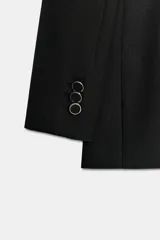 Blazer de corte estructurado con hombreras, cuello de solapa y manga larga. Presenta un diseño cruzado con cierre frontal de botones y bolsillos delanteros con solapa.