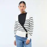 Sweater de punto con diseño cruzado tipo cárdigan, de manga larga y cuello en V. Presenta un estampado de rayas horizontales negras sobre fondo blanco, con bordes negros y un botón dorado decorativo en el frente.