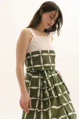 Top de tirantes anchos con diseño bicolor, presentando una parte superior en color crudo y una parte inferior en verde con estampado geométrico de líneas blancas.