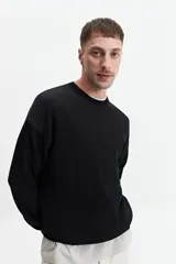 Buzo de punto oversize color negro, con escote redondo y puños.