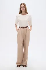 Pantalón de lyocell color beige, de tiro alto, corte ancho y diseño plisado con bolsillos laterales.