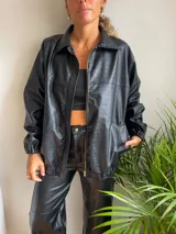 Campera negra de cuero sintético con textura crocco, cierre frontal con cremallera y cuello camisero.