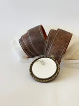 Cinto de cuero color marrón con forro de cuero y hebilla redonda con detalles de guampa. El broche es suizo, para poder usar el cuero con otras hebillas.