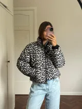 Campera puffer con estampado de leopardo en tonos blanco y negro, cuello alto, cierre frontal y bolsillos laterales.