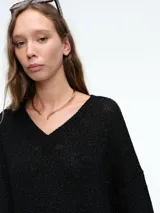 Sweater de punto con brillo, de corte relajado y escote en V. Presenta hombros caídos y mangas largas con puños acanalados.