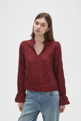 Blusa de viscosa color bordó con diseño bordado geométrico, cuello en V y mangas largas con terminación en volados.