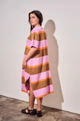 Vestido midi de tejido de punto con diseño de rayas horizontales en tonos rosa, naranja y marrón. Presenta cuello redondo, mangas cortas y un corte holgado con aberturas laterales en el ruedo.