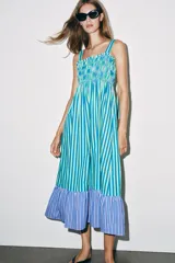 Vestido midi de escote recto con cuerpo de nido de abeja elástico, tirantes anchos con lazos y falda larga con volados en el borde inferior. Presenta un estampado de rayas verticales en tonos verde, azul y blanco.