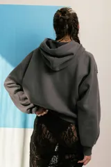 Campera negra con cierre frontal, capucha y mangas largas con aberturas en los hombros.