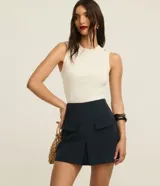 Short pollera de cintura alta color azul marino, confeccionado en tejido plano. Presenta solapas delanteras simulando bolsillos y un recorte en V en el ruedo.