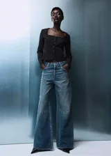 Jeans de tiro medio con diseño wide leg, confeccionados en tejido de algodón estilo tejano. Presentan un acabado con adorno de strass, cierre de botones y cinco bolsillos.