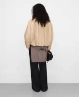 Chaqueta boxy acolchada de algodón en color beige, con cuello italiano de piel ovina en contraste, manga larga con hombro caído y bajo abullonado. Cuenta con cierre de botones y bolsillos de vivo inclinados en el delantero.