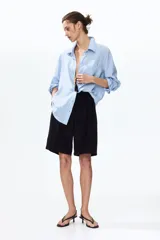 Camisa en tejido liviano de mezcla de lino y viscosa, a rayas celestes y blancas, con cuello, botones delanteros y bolsillo superior abierto. Modelo de manga larga con puños abotonados y bajo redondeado.