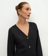 Cardigan de punto color negro con escote en V, cierre frontal con botones, mangas largas con puños acanalados y bolsillos frontales funcionales.
