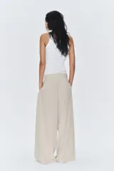 Pantalón de tiro medio color marrón, con pinzas en el delantero, perneras anchas de corte recto y trabillas para cinturón. Cuenta con bolsillos laterales y traseros, y cierre frontal con cremallera y botón.