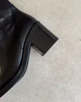 Botín corto de cuero color marrón oscuro, con punta cuadrada y taco ancho acanalado.