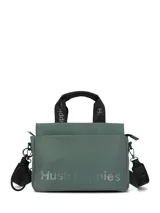 Cartera tipo tote de color verde, con logo de la marca Hush Puppies estampado en el frente. Cuenta con doble asa de mano y una correa ajustable extraíble, ambas con el nombre de la marca grabado. Presenta herrajes metálicos en color negro.