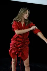 Vestido corto de lino rojo con escote en V, mangas largas y sistema de jaretas ajustables con cordones frontales para fruncir y regular el largo.